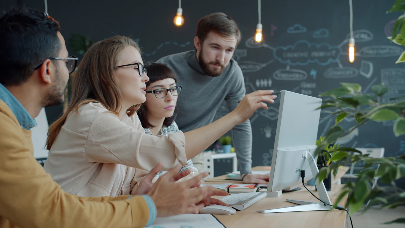 Equipe colaborando ao redor de um computador, ilustrando Sobre a CodeIA